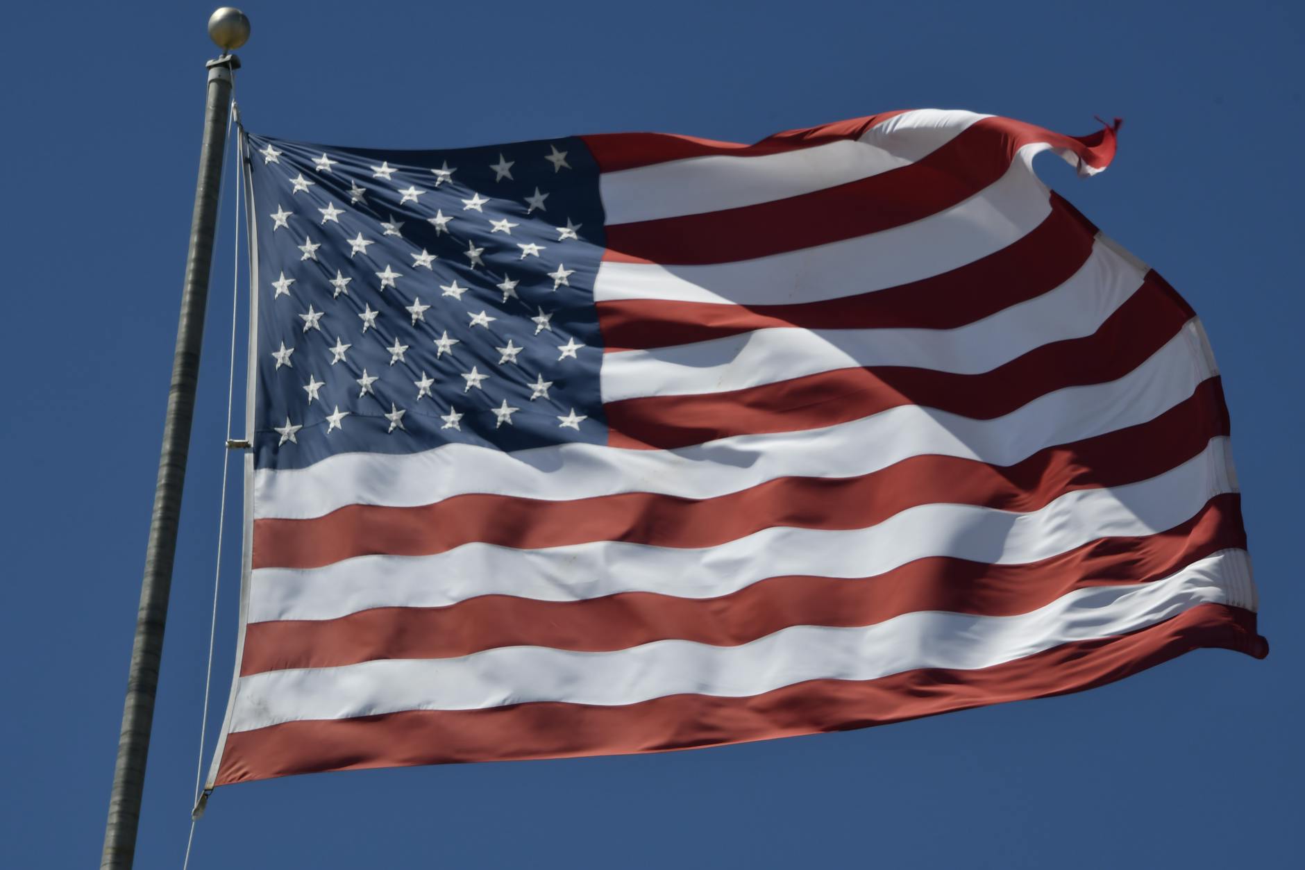 us flag waving against clear blue sky